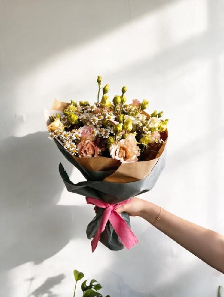 Ramo de lisianthus, rosas e camomila embrulhado em papel kraft com laço cor-de-rosa